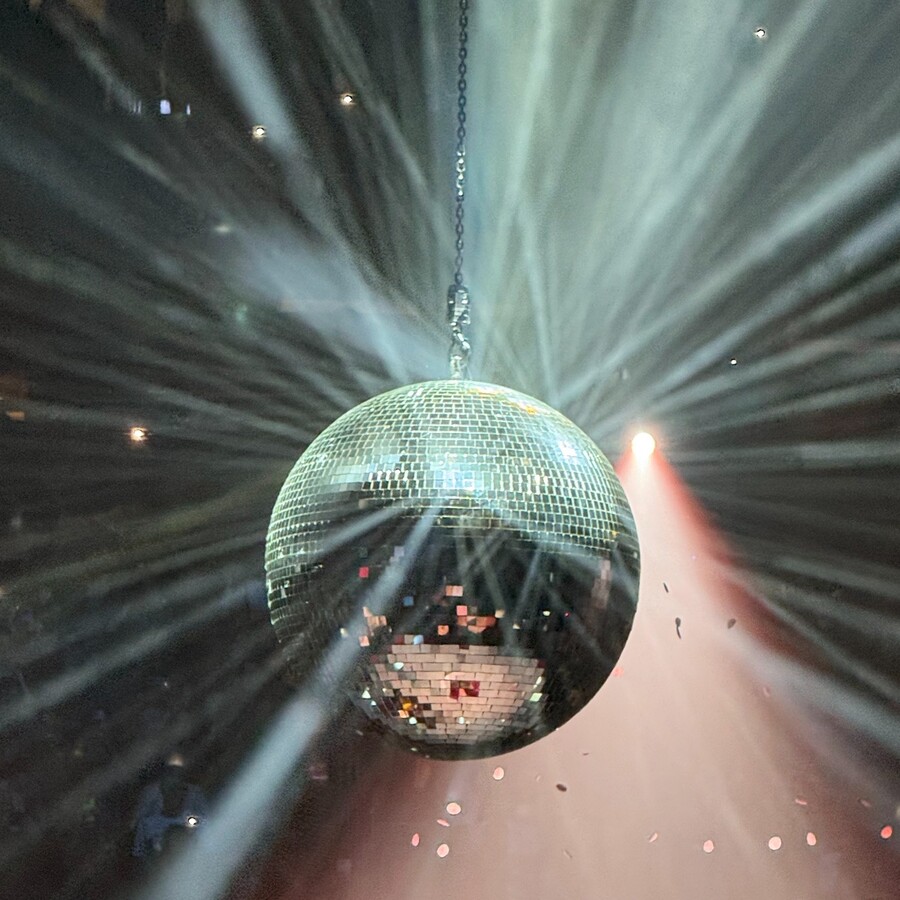 A mirrored disco ball casting beams of light across a dark room